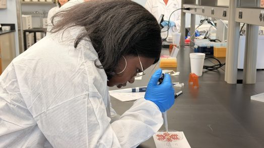 A female high school student learns how to use lab equipment during a field trip to a scientific lab.
