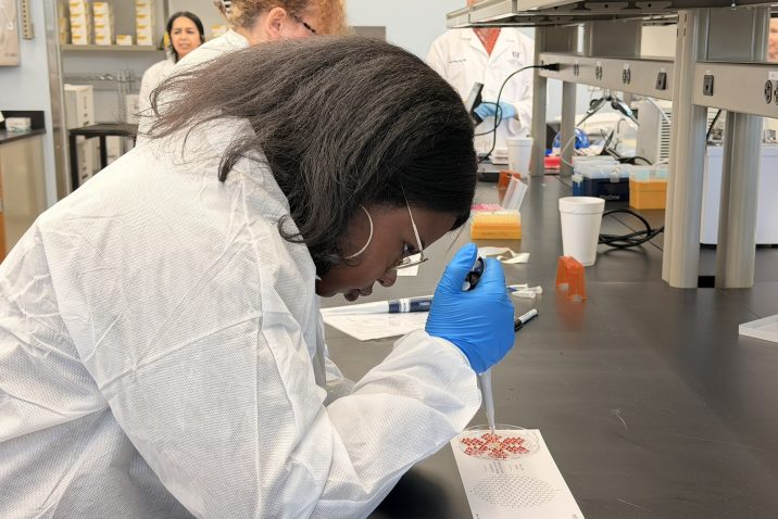 A female high school student learns how to use lab equipment during a field trip to a scientific lab.