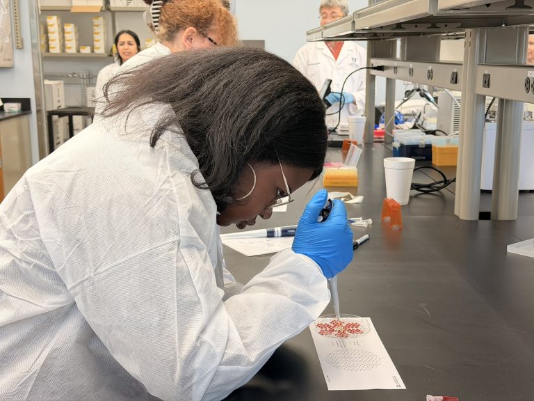 A female high school student learns how to use lab equipment during a field trip to a scientific lab.