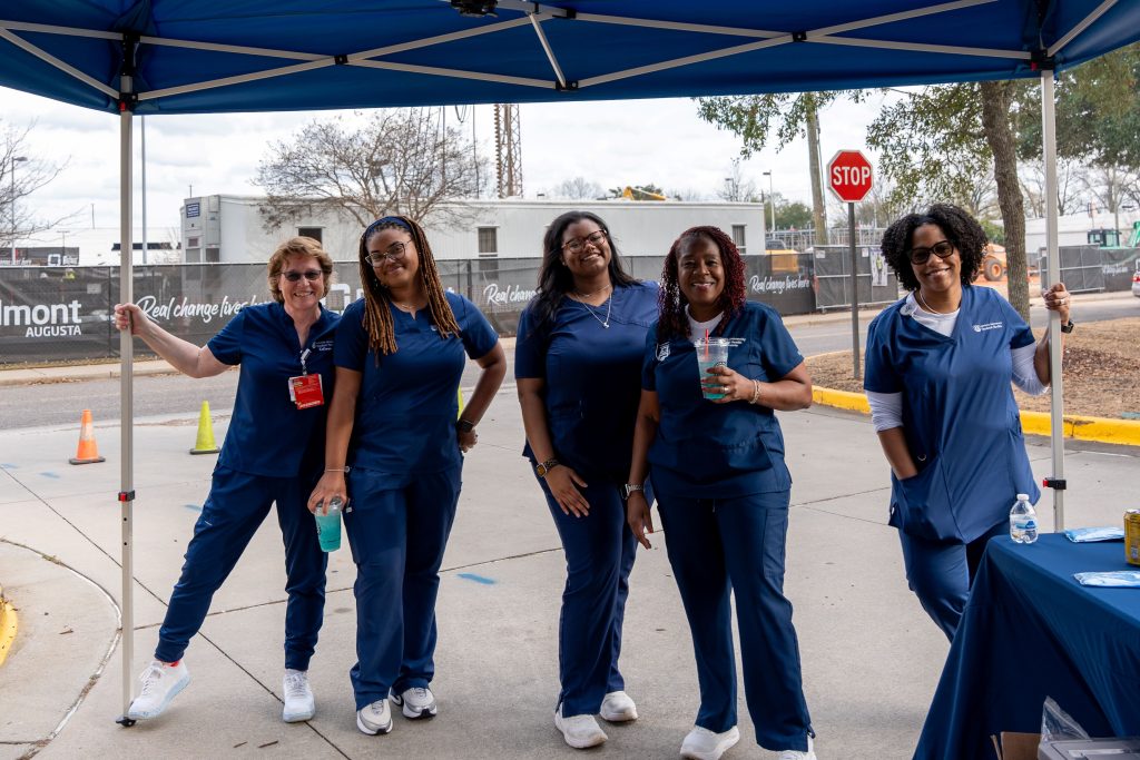 A group of women dressed in medical scrubs pose for a picture.