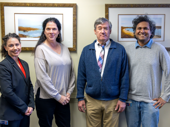 Two men and two women stand in a conference room.