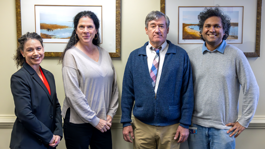 Two men and two women stand in a conference room.