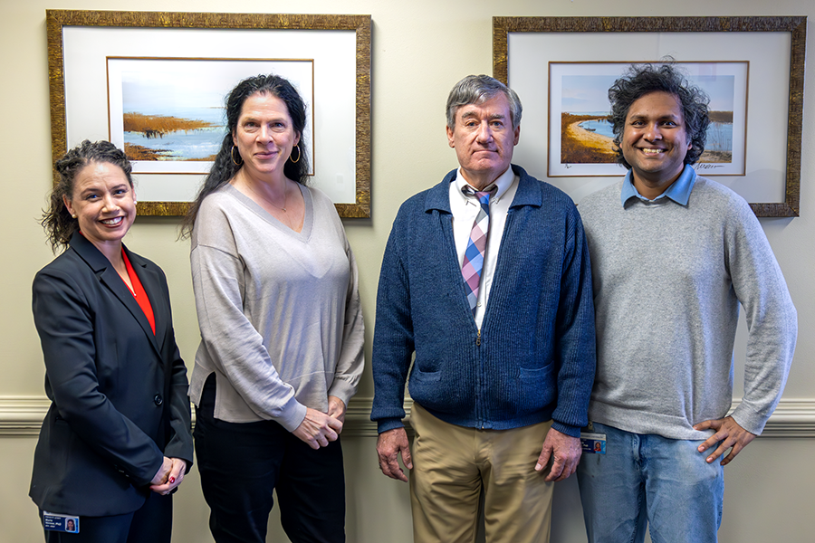 Two men and two women stand in a conference room.