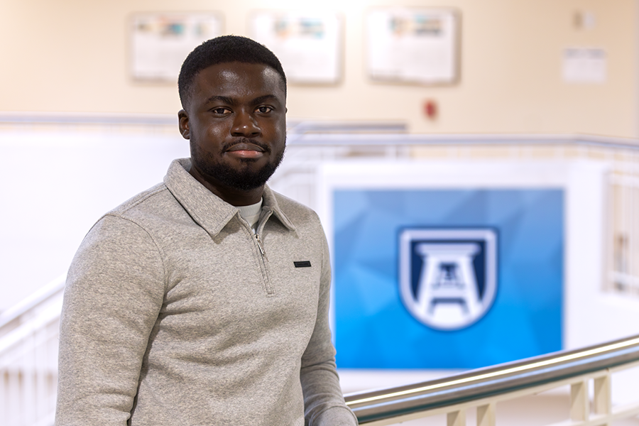 A male college student stands in a hallway.
