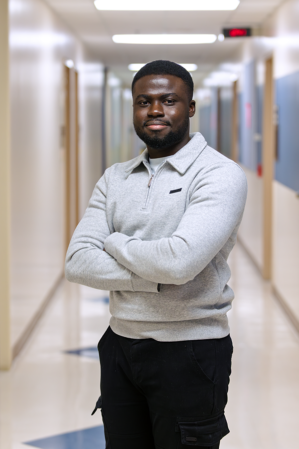 A male college student stands in a hallway.