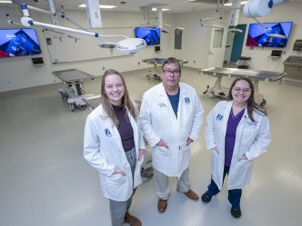 Two women and a man standing in a room