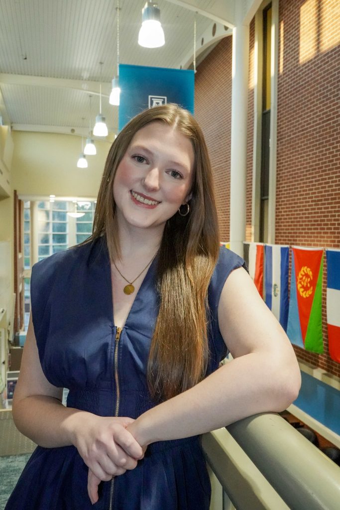 With an arm propped on a stairwell, a girl smiles for a photo.