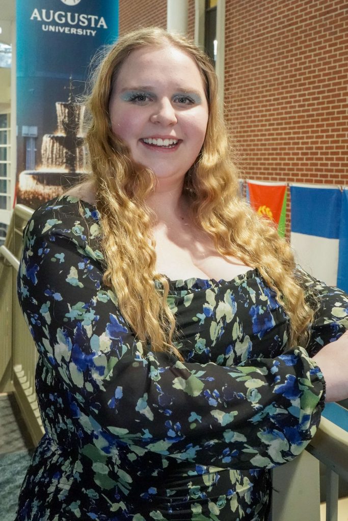With an arm propped on a stairwell, a girl smiles for a photo.