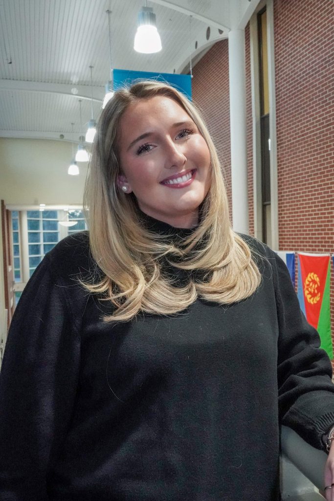 With an arm propped on a stairwell, a girl smiles for a photo.