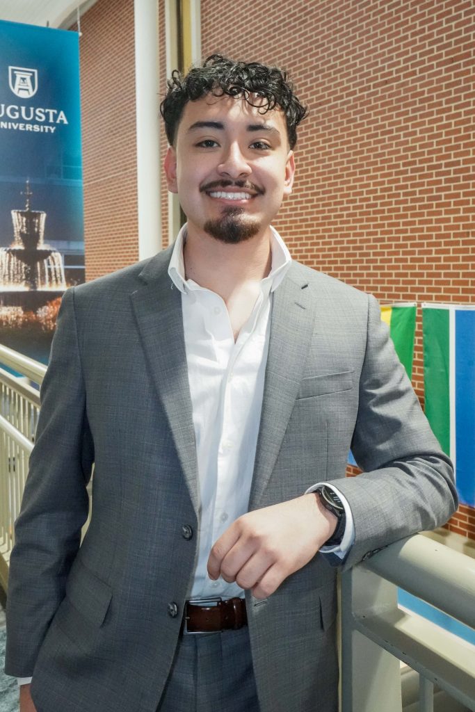 With an arm propped on a stairwell, a guy smiles for a photo.