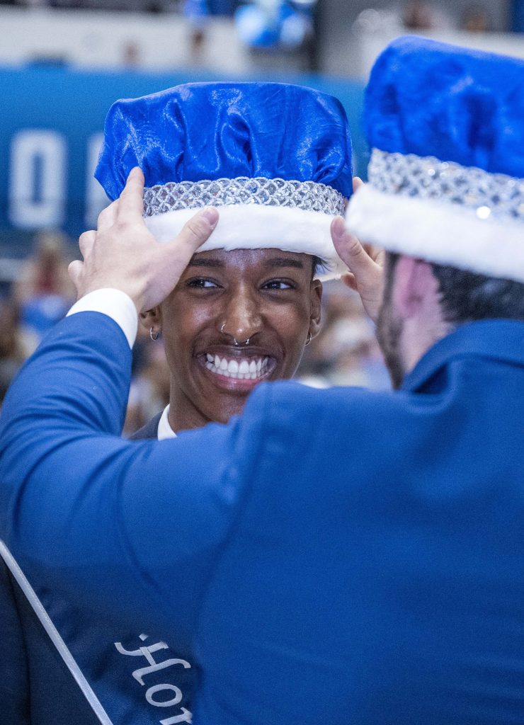 A man places a crown on the top of another man's head.