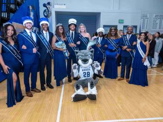 Men and women dressed in formal form a semi-circle around Augusta University's mascot Augustus.
