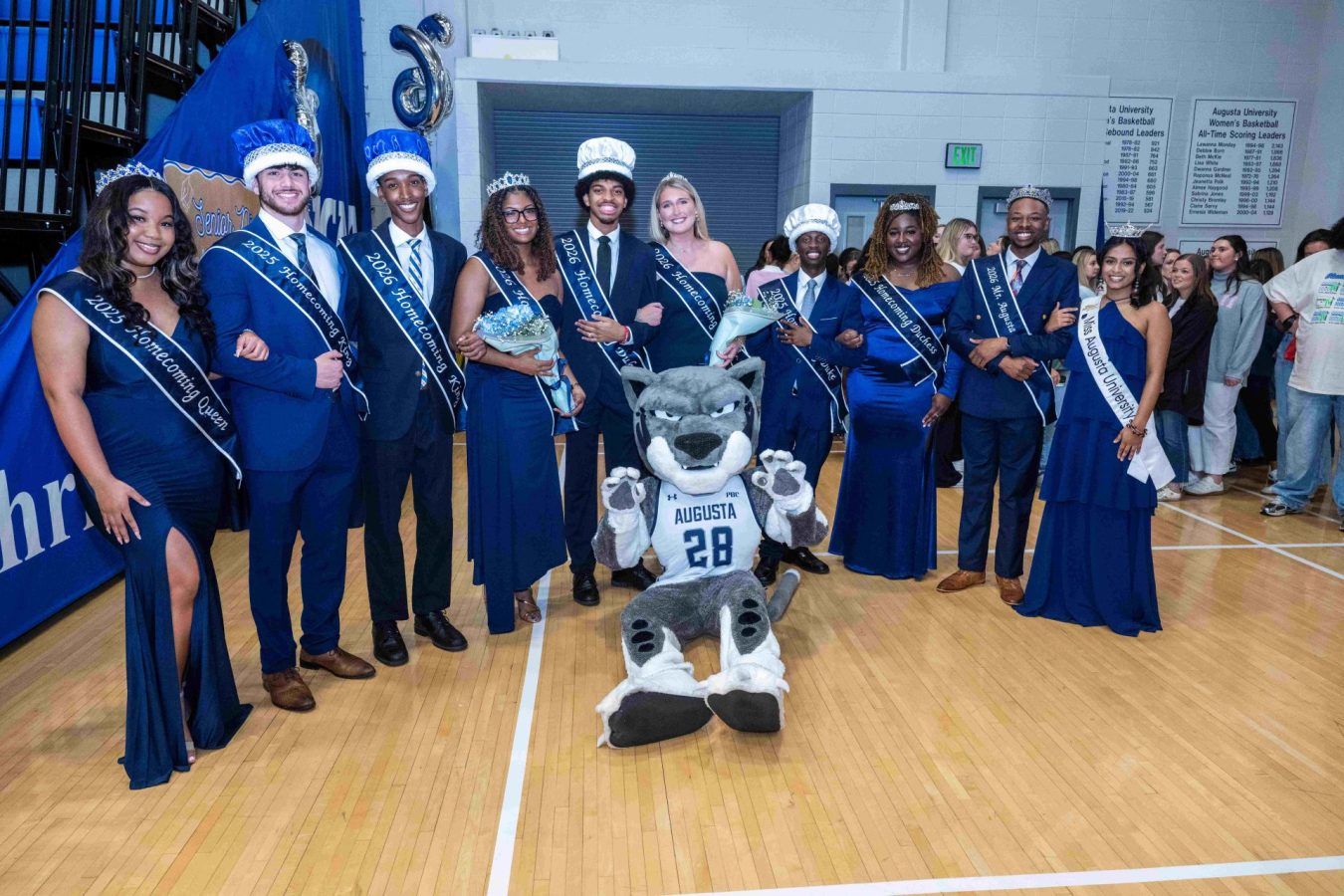 Men and women dressed in formal form a semi-circle around Augusta University's mascot Augustus.