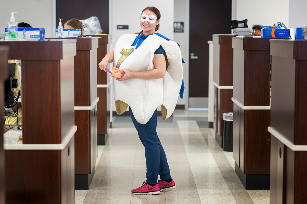 A female dental hygiene student dressed in a tooth costume smiles for a picture.