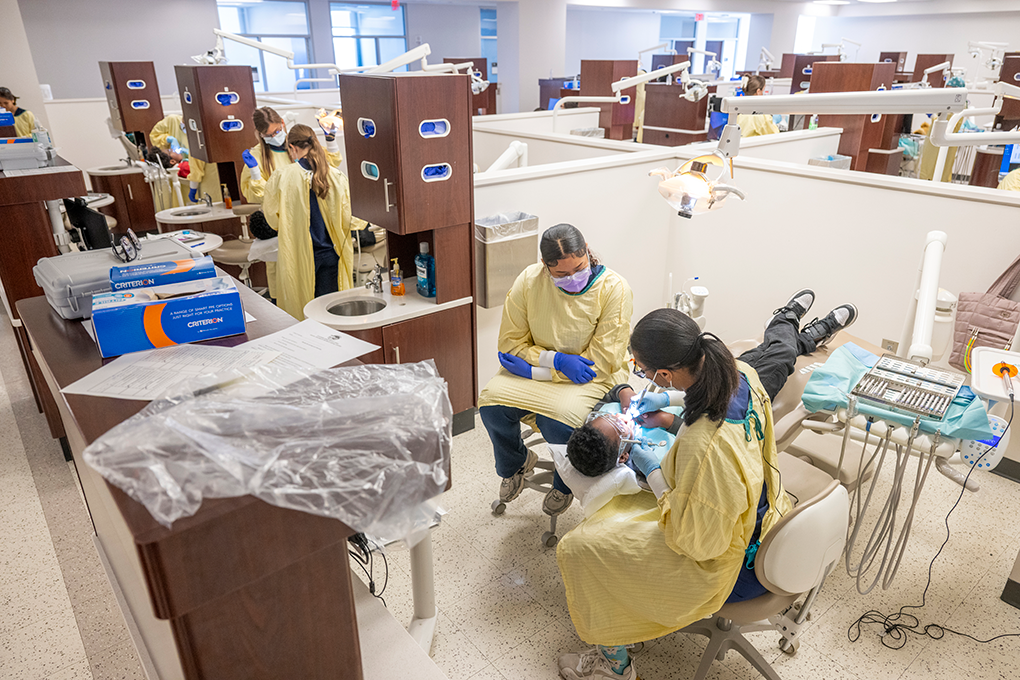 An overview photo of dental hygiene students cleaning kids' teeth.