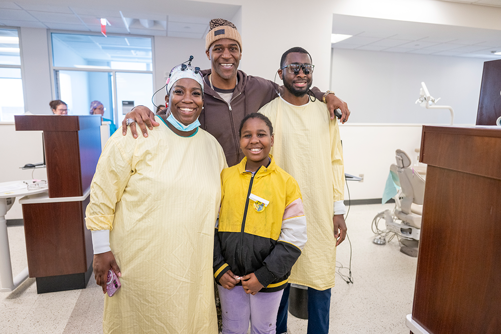 Two dental hygienists, a former NFL football player and a young girl smile for a picture.