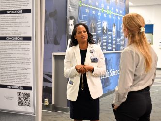 Two women talking in front of an informative poster
