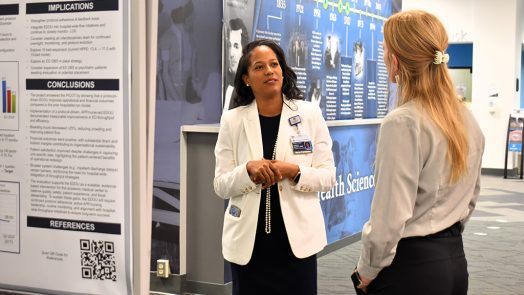 Two women talking in front of an informative poster
