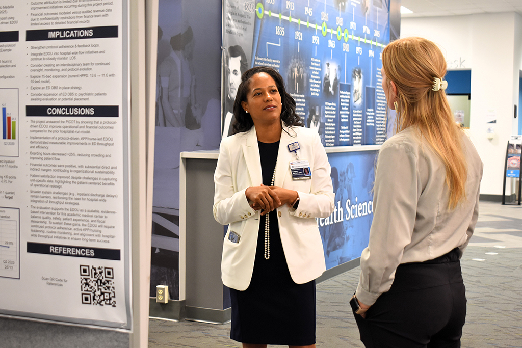 Two women talking in front of an informative poster