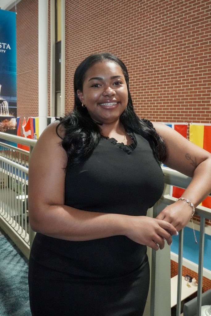 With an arm propped on a stairwell, a girl smiles for a photo.