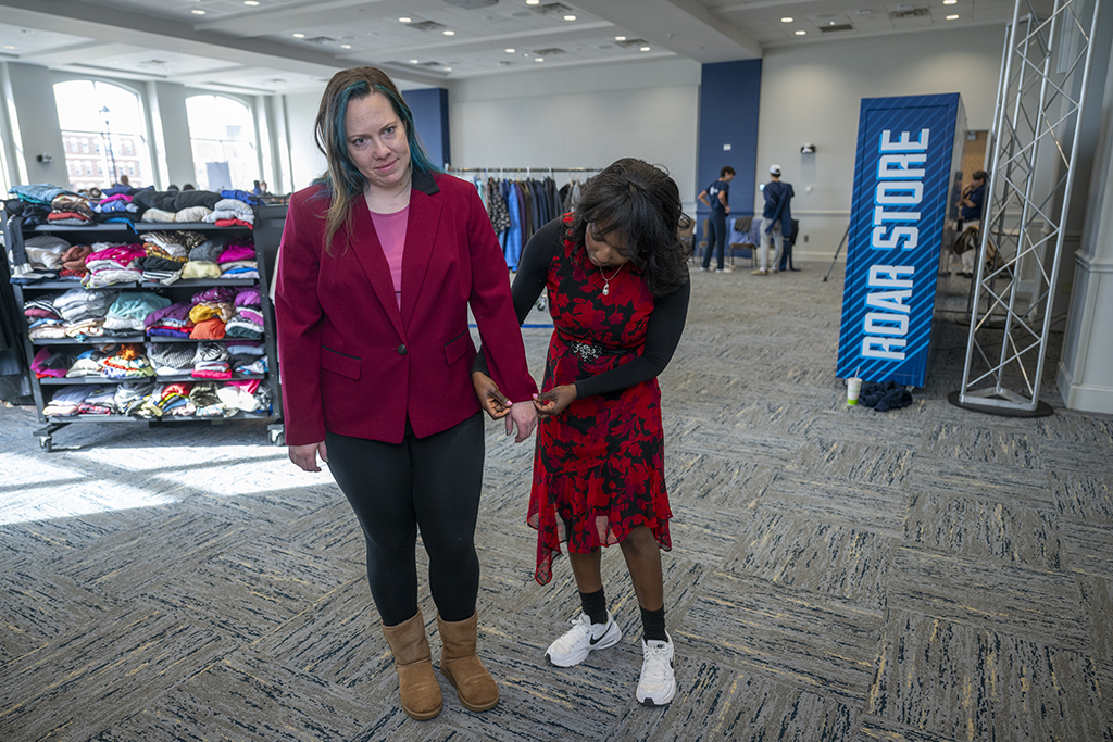 A woman helping another women try on clothes