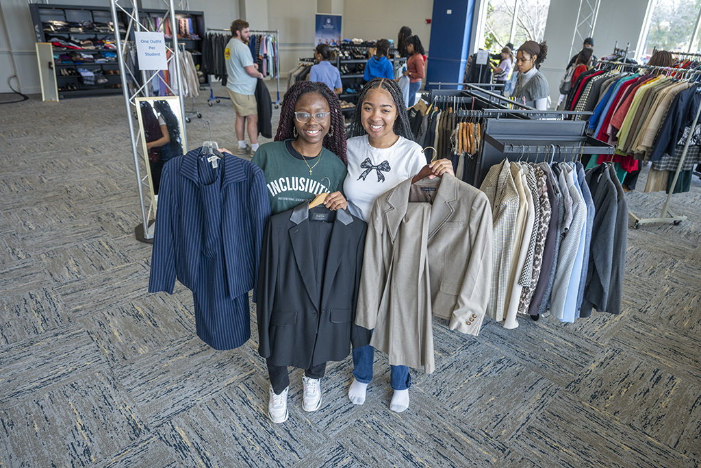 Two women holding up clothing