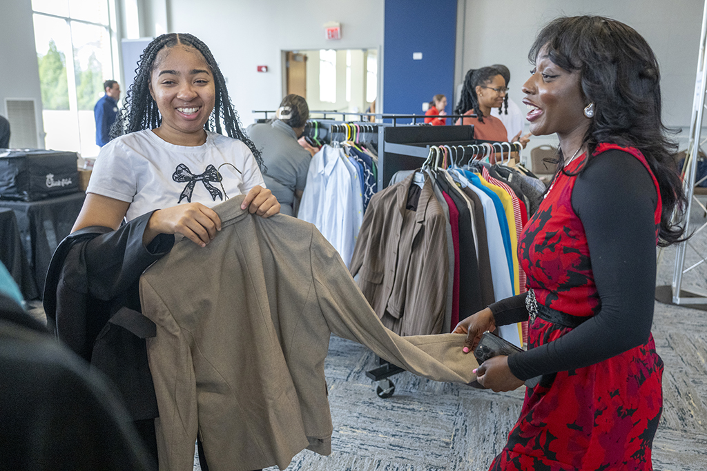 A woman helping another women look at clothes