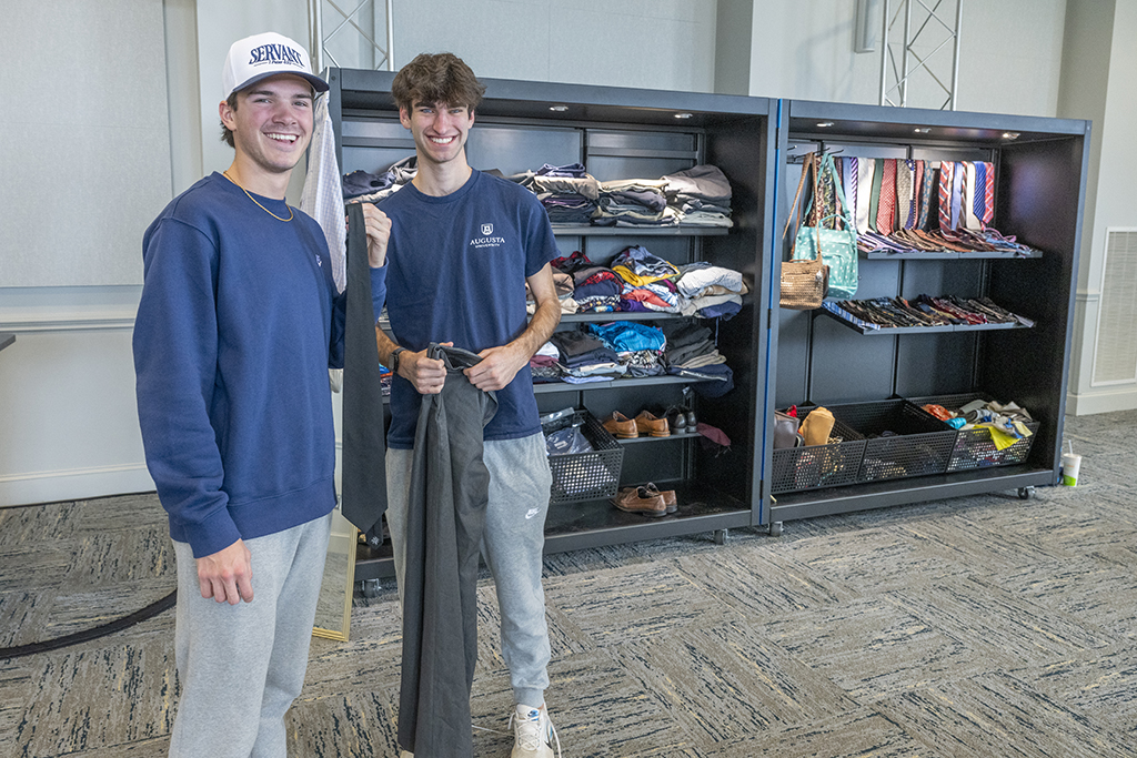 Two men holding up clothes