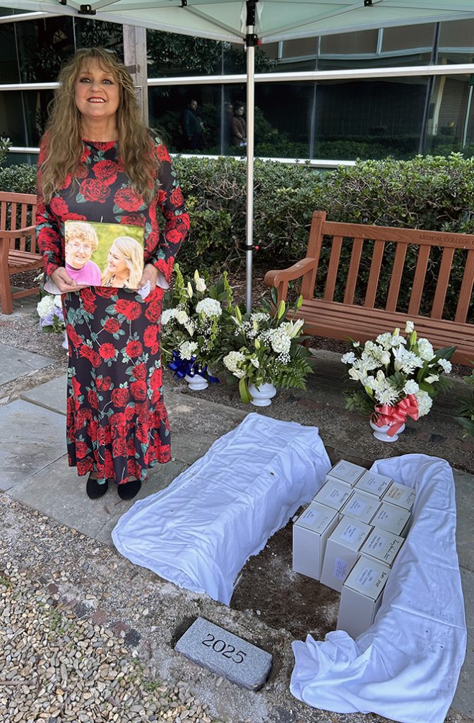 Woman holding a photo near a burial site