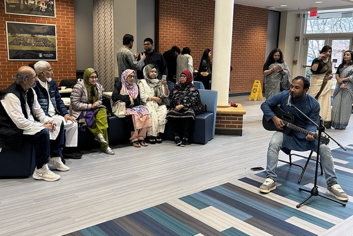 Man playing a guitar while men and women listen