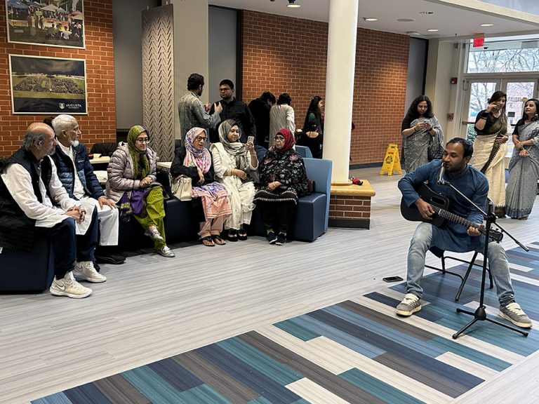 Man playing a guitar while men and women listen