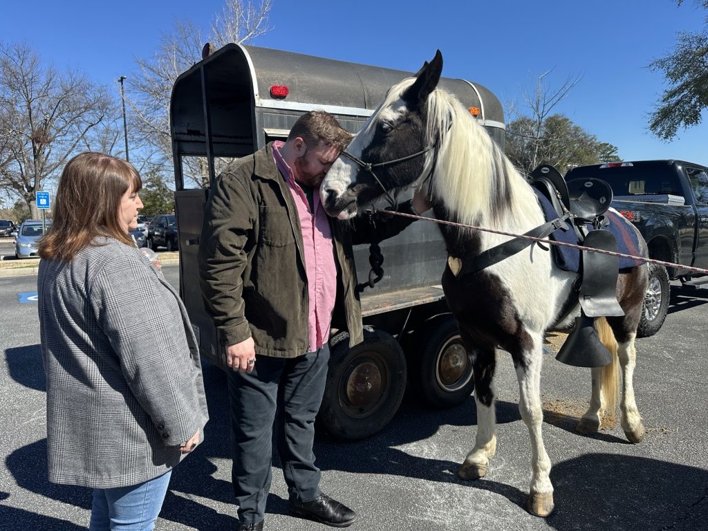 A man pressing his face against a horse.
