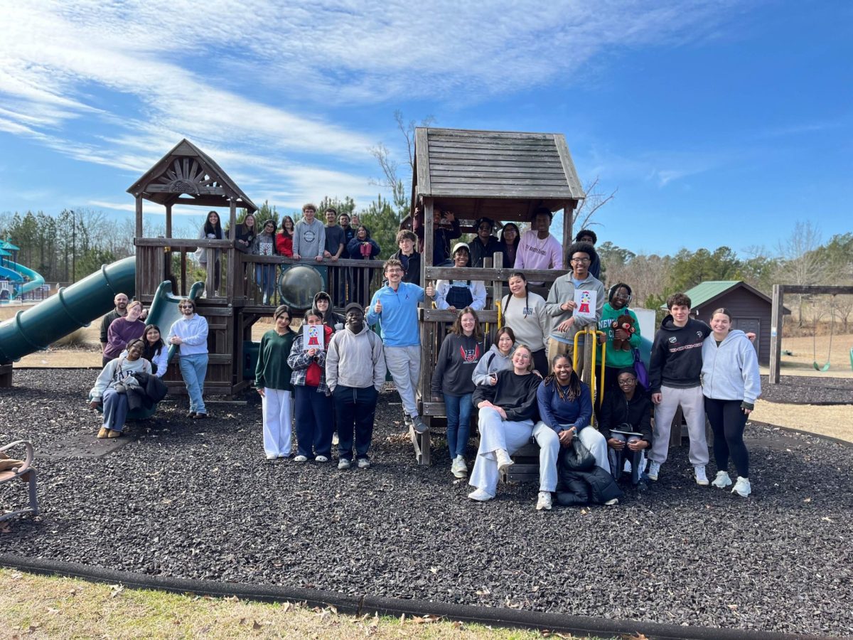 A large group and men and women on a children's playground pose for a photo.