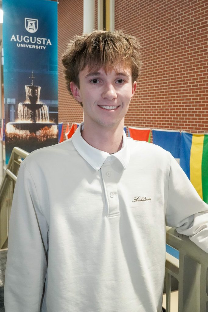 With an arm propped on a stairwell, a guy smiles for a photo.