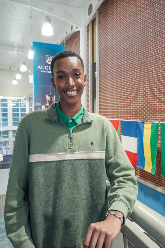 With an arm propped on a stairwell, a guy smiles for a photo.