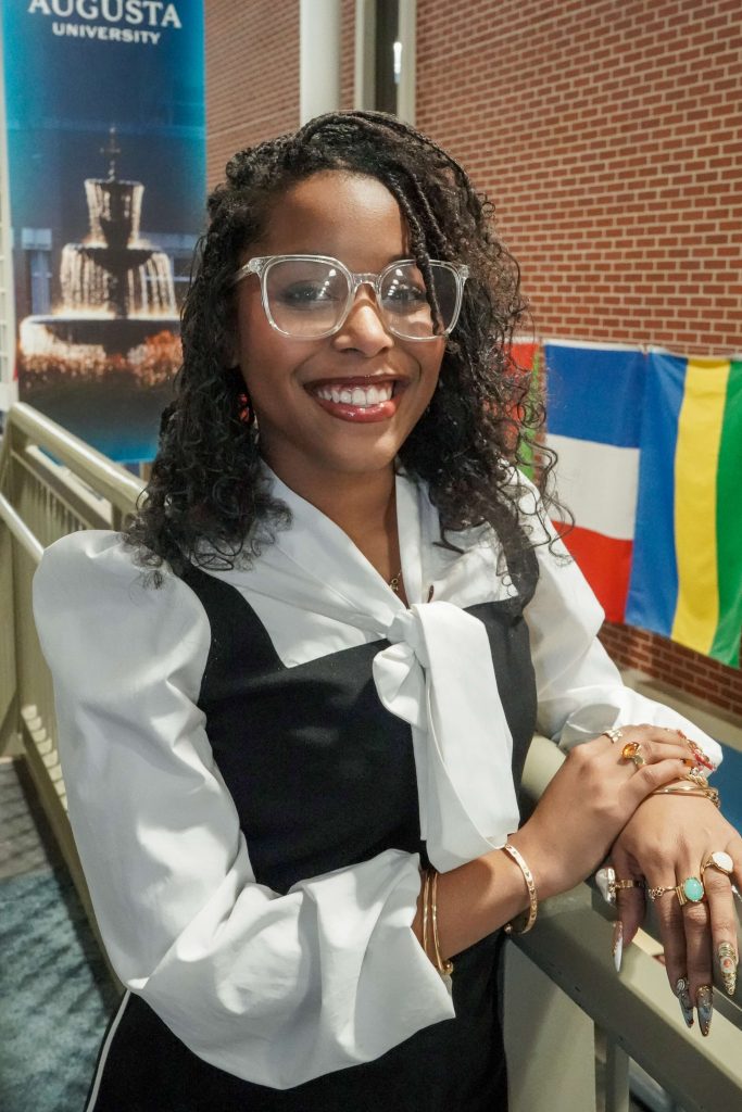 With an arm propped on a stairwell, a girl smiles for a photo.