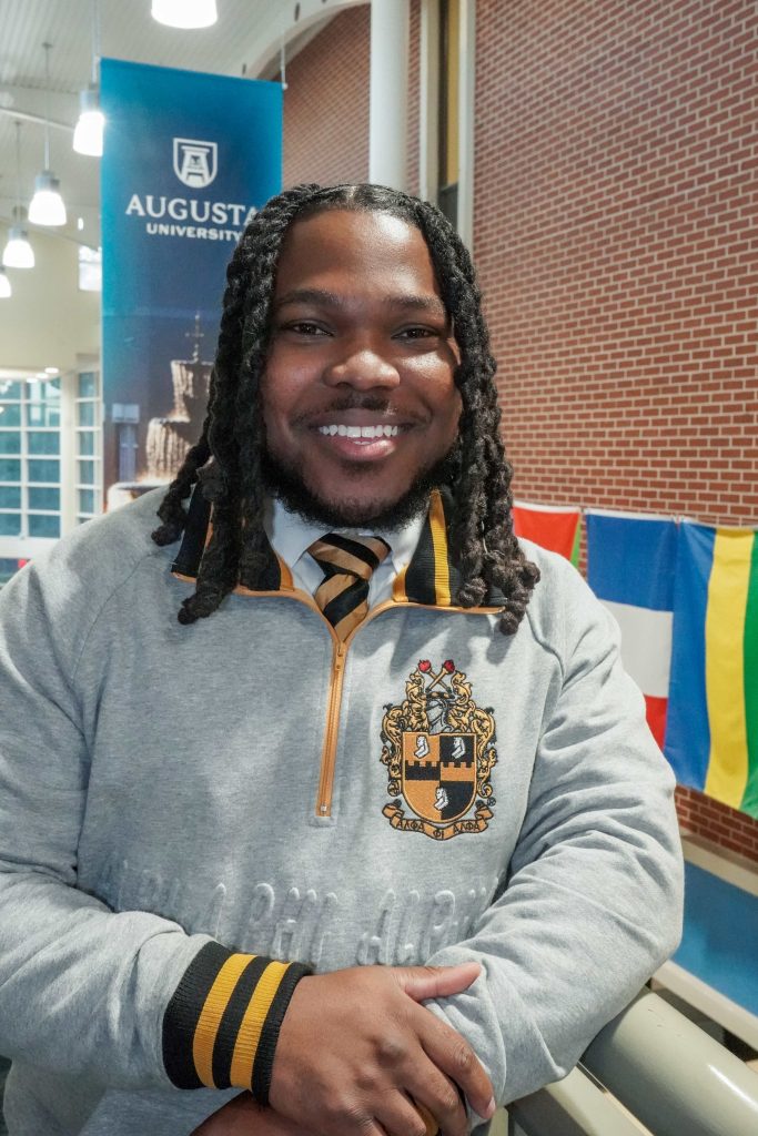 With an arm propped on a stairwell, a guy smiles for a photo.