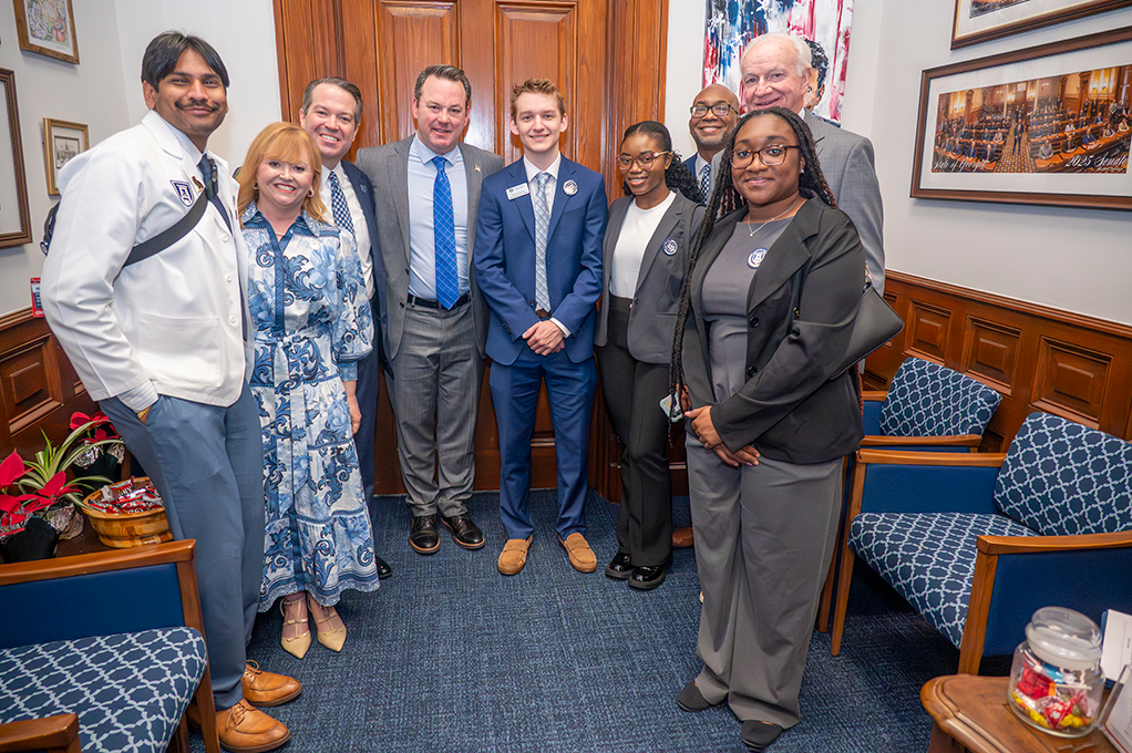 Six men and three women gather closely smiling in various business dress.