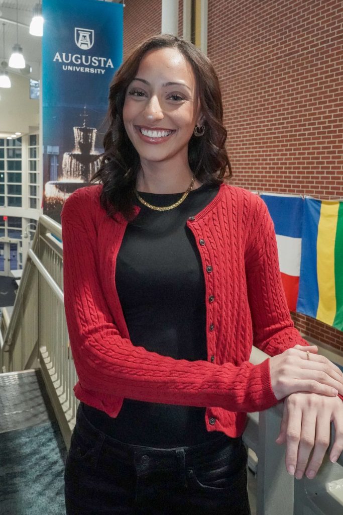 With an arm propped on a stairwell, a girl smiles for a photo.