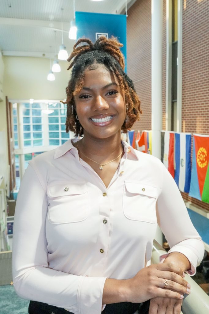 With an arm propped on a stairwell, a girl smiles for a photo.