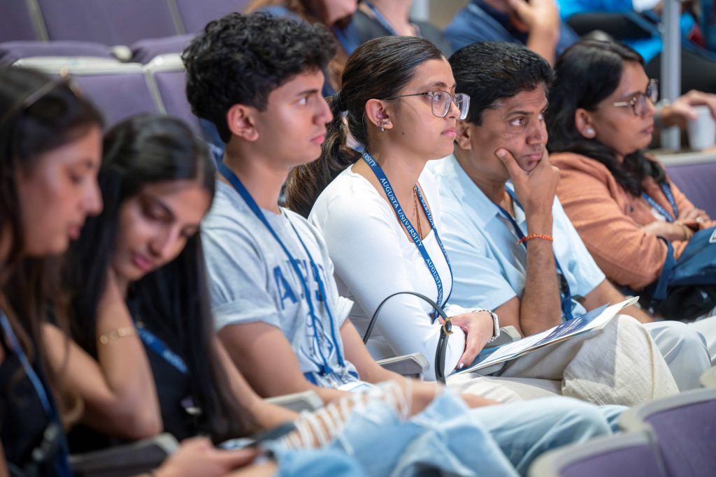 A close up of a family sitting beside one another while listening to a speaker.