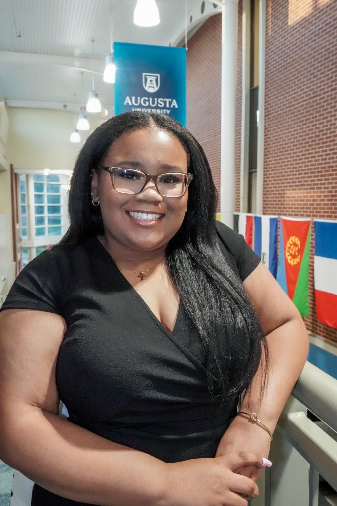 With an arm propped on a stairwell, a girl smiles for a photo.