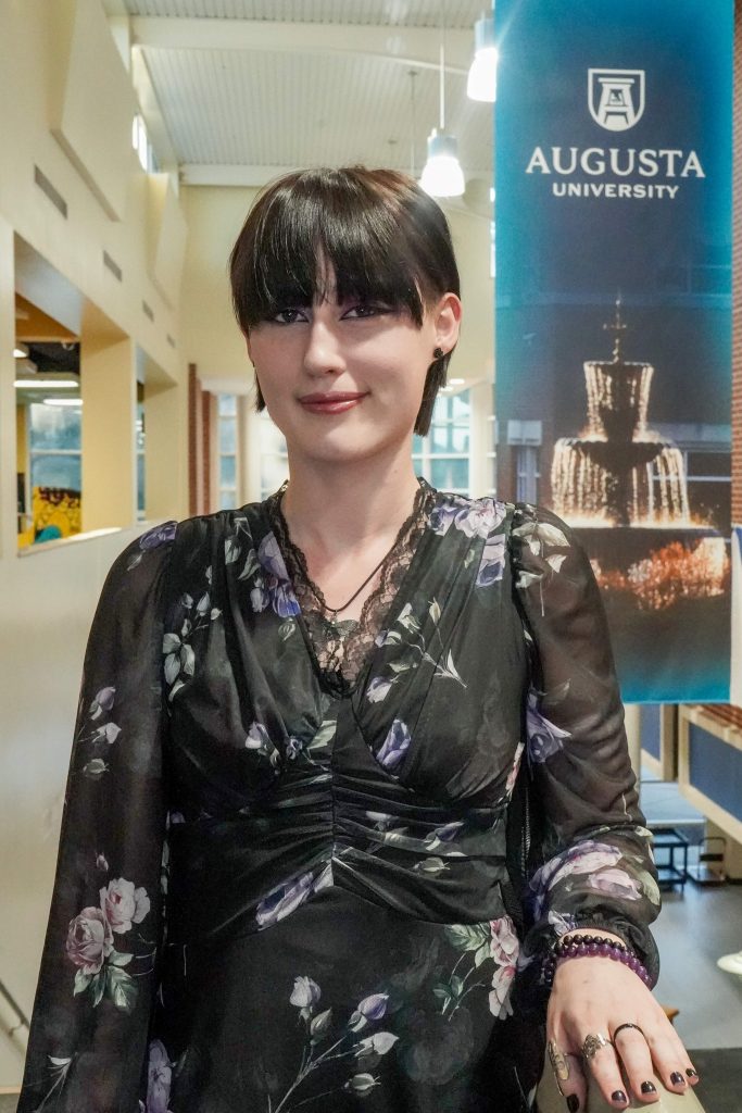 With an arm propped on a stairwell, a girl smiles for a photo.