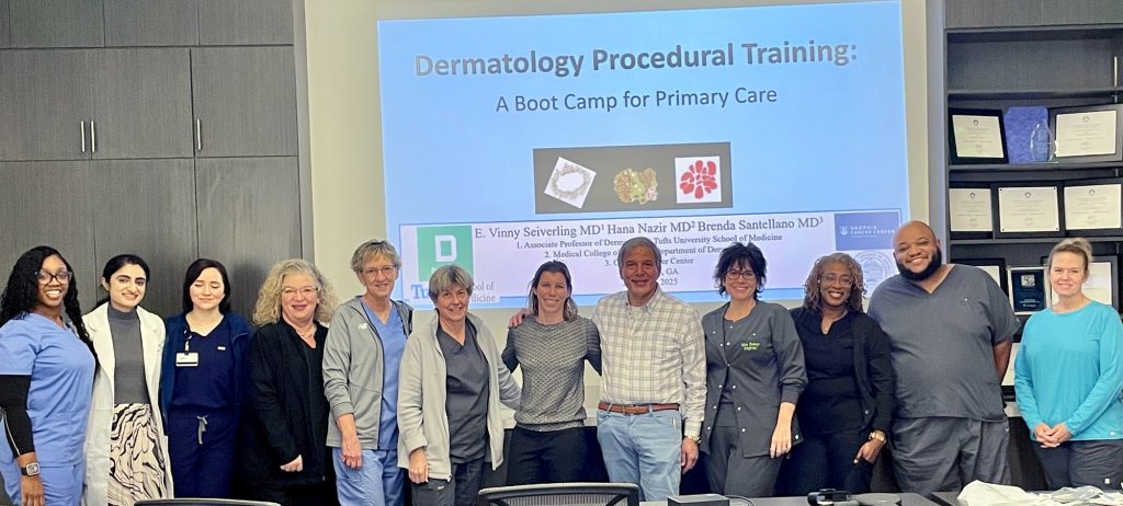 In this photo, you see a group of men and women standing and posing for a photo in front of a projector screen.