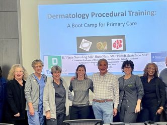 In this photo, you see a group of men and women standing and posing for a photo in front of a projector screen.