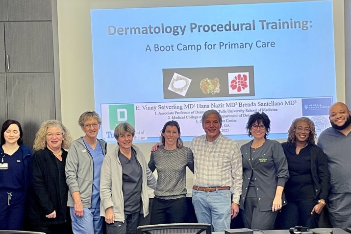 In this photo, you see a group of men and women standing and posing for a photo in front of a projector screen.