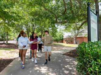 Several students walking down a shaded path.