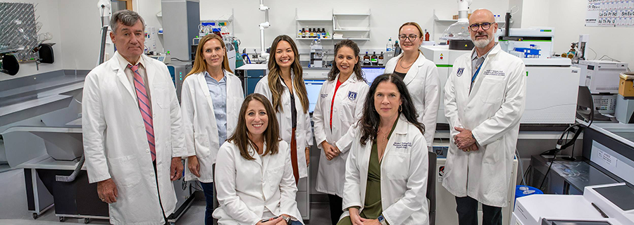 A group of eight scientists stand in a scientific lab.