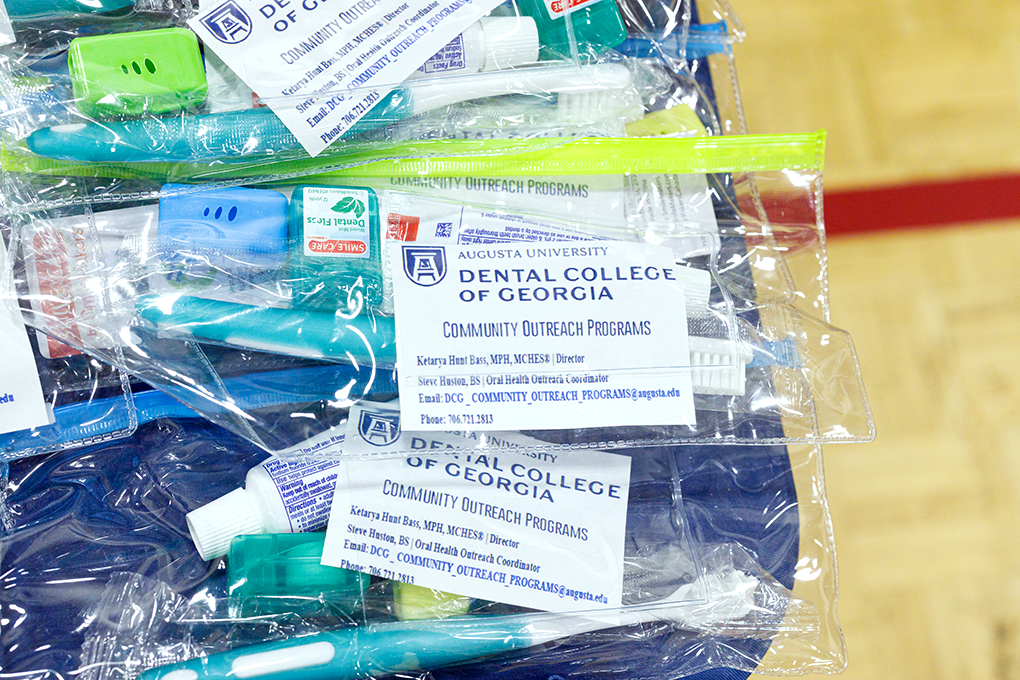 A close up of small plastic bags with toothbruses, toothpaste, and other dental hygiene items in them. A label on them reads, "Dental College of Georgia."