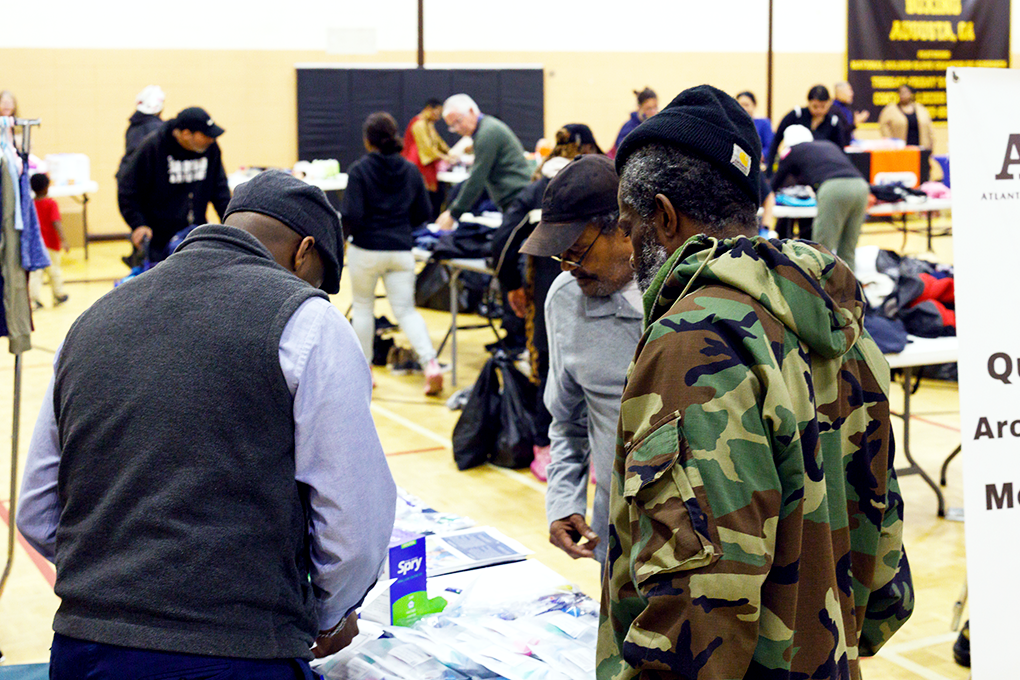Three men stand around a table at a community even for people in need.